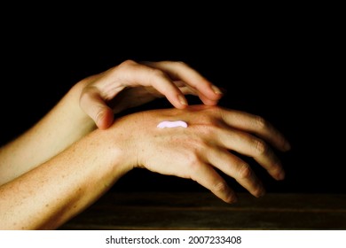 Female Hands With Small Dose Of Cream On The Back, Dark Background.