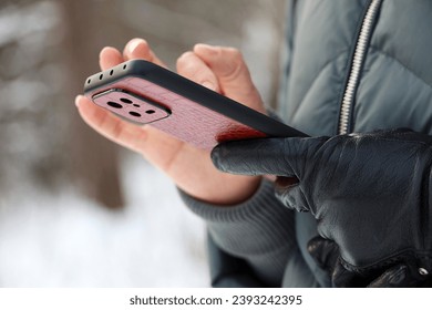 Female hands with smartphone close up on blurred background. Woman using mobile phone stands on a street in snow winter - Powered by Shutterstock