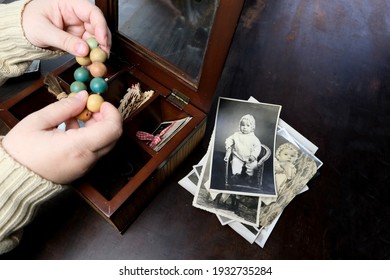 Female Hands Are Sorting Dear To Heart Memorabilia In An Old Wooden Box, A Stack Of Retro Photos, A Wooden Rosary, Vintage Photographs Of 1960, Concept Of Family Tree, Genealogy, Childhood Memories