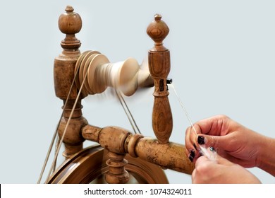 Female hands spin a woolen thread on an old wooden spinning wheel. - Powered by Shutterstock