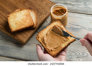 Female hands spread peanut butter on toast close-up. - Powered by Shutterstock