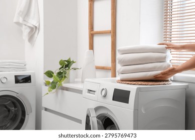 Female hands with stack of clean bed sheets in bathroom