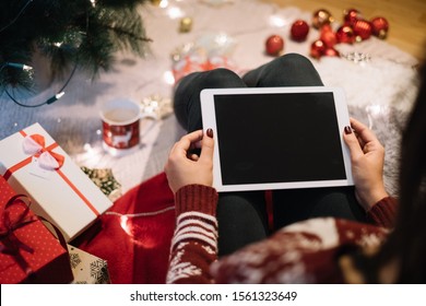 Female hands with tablet near Christmas tree - Powered by Shutterstock