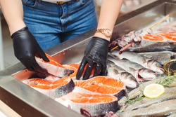 Female Hands Take Salmon Steak From Showcase. Fish Food At Shop, Close Up. Raw Fish Ready For Sale In The Supermarket. Showcase With Chilled Red Fish In Grocery Store. Market Place With Sea Food.