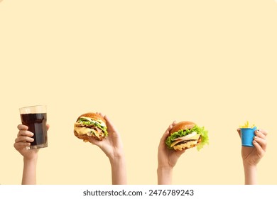 Female hands with tasty burgers, french fries and glass of cola on light yellow background - Powered by Shutterstock