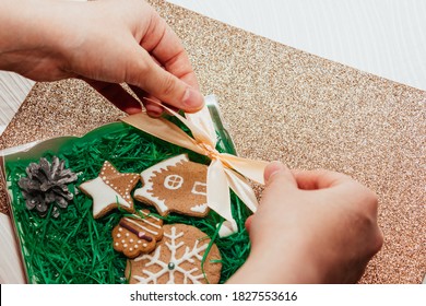 Female hands tie gift bow on a gift box of ginger cookies. Christmas gift - Powered by Shutterstock