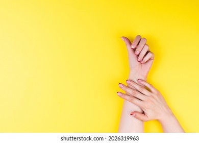 Female hands with a trendy autumn french manicure with red tips at the free edge of the nail. Ultimat yellow background
