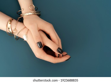 Female hands with trendy dark nail design with gold bracelets on aqua background. Luxury concept. Festive backdrop for your design. Top view. - Powered by Shutterstock