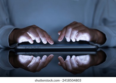 female hands typing on a tablet in a dark office room, close-up - Powered by Shutterstock