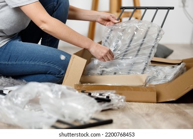 Female Hands Are Unpacking A Cardboard Box, Assembling New Furniture.