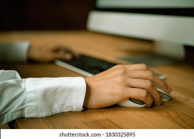 Female hands using computer mouse and keyboard. Selective focus on arm in foreground. Close-up shot. High quality photo.