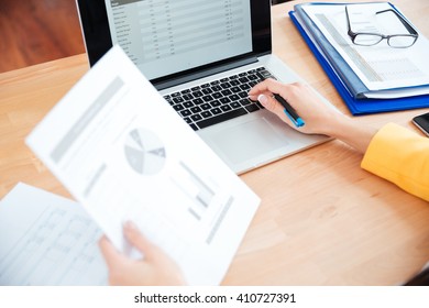Female hands using laptop computer and holding documents - Shutterstock ID 410727391