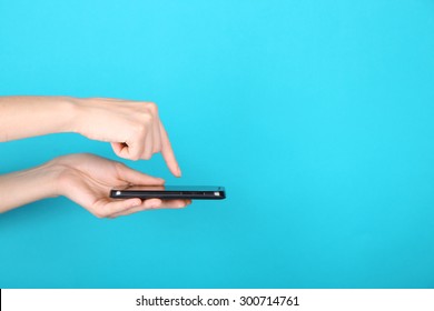 Female Hands Using Mobile Phone On Blue Background