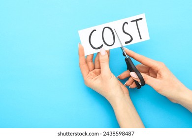 Female hands using scissors for cutting word Cost