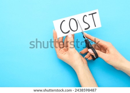 Female hands using scissors for cutting word Cost