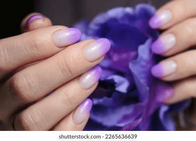 Female hands and violet nail design close  up  Artistic manicure and gradient violet glitter nail polish