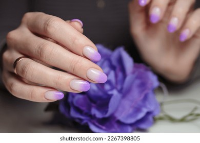 Female hands and violet nail design close  up  Artistic manicure and gradient violet glitter nail polish