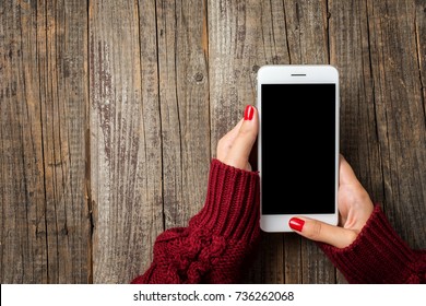 Female Hands In Warm Sweater Holding White Smart Phone