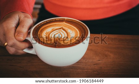 Female hands in warm sweater holding cup of coffee. Close up