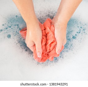 Weibliche Hände, die farbige Kleidung im Waschbecken waschen