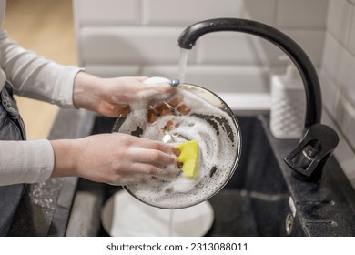 female hands washing dirty dish holding soap foam sponge in the kitchen 