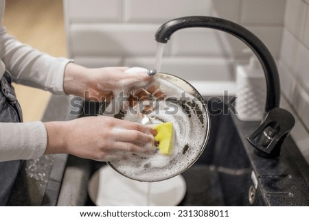 female hands washing dirty dish holding soap foam sponge in the kitchen 