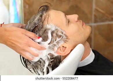 Female hands washing hair to handsome smiling man at hairdresser with shampoo before haircut. Keratin restoration, latest trend, fresh idea, haircut picking, shorten tips, instrument store concept