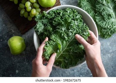 Female hands washing kale cabbage in bowl of water. Cooking healthy organic home grown vegan food, top view - Powered by Shutterstock