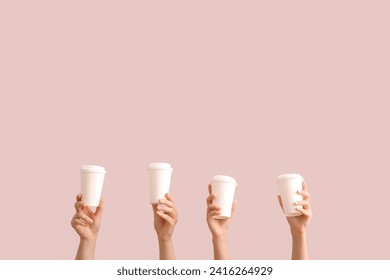 Female hands with white takeaway paper cups on purple background
