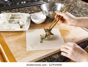 Female Hands With Wooden Chopsticks Putting Fresh Food Ingredients On To Spring Roll Wrap