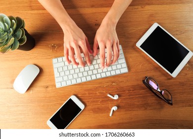 Female hands working with modern white keyboard and mouse on wooden background, top view 