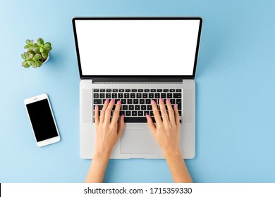Female hands working on laptop with empty display. Office desktop with accessories. Top view