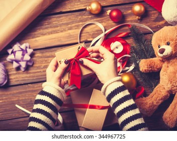 Female hands are wrapping a christmas gift on wooden background - Powered by Shutterstock