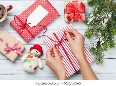 Female Hands Wrapping Christmas Gift Box Above Wooden Table. Top View