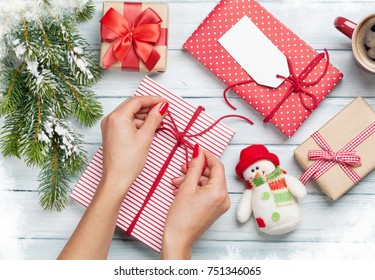 Female Hands Wrapping Christmas Gift Box Above Wooden Table. Top View
