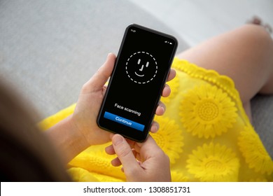 Female Hands In Yellow Dress Holding Phone With Face ID Scanning On Screen