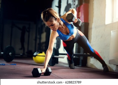 Female Hard Work At Gym With Dumbbells Push Ups. Strong Woman At Gym.