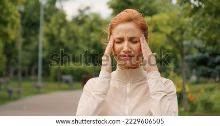 Female having a headache while jogging. Woman stops running because a head pain. Severe migraine concept. Emotions of strong suffering. Pills prescription, fitness training health problems.