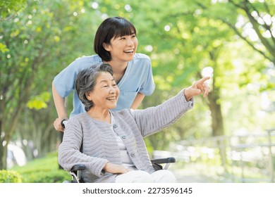 Female Healthcare Professional Pushing Senior Female Wheelchair - Powered by Shutterstock