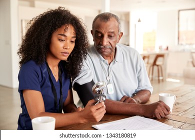 Female healthcare worker checking the blood pressure of a senior man during a home visit