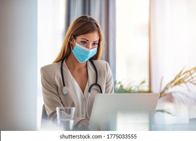 Female Healthcare Worker Counseling, Helping Patient Online In Her Office. Wearing Protection Mask During Corona Virus Outbreak. Mid Adult Female Doctor Working In Office. 