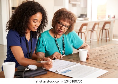 Female healthcare worker filling in a form with a senior woman during a home health visit - Powered by Shutterstock