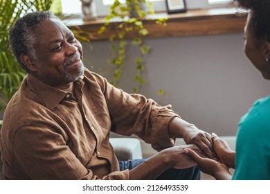 Female Healthcare Worker Holding Hands Of Senior Man At Care Home, Focus On Hands. Doctor Helping Old Patient With Alzheimer's Disease. Female Carer Holding Hands Of Senior Man