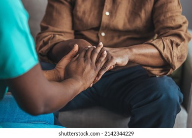 Female Healthcare Worker Holding Hands Of Senior Man At Care Home, Focus On Hands. Doctor Helping Old Patient With Alzheimer's Disease. Female Carer Holding Hands Of Senior Man