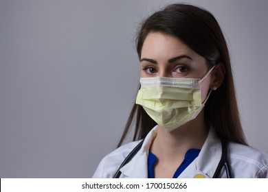 Female healthcare worker wearing mask isolated on grey background. Space for copy or text. Wearing stethoscope and white coat.