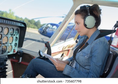 Female Helicopter Pilot Reading A Manual While Sitting In Cockpit