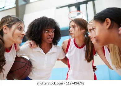 Female High School Basketball Players In Huddle Having Team Talk With Coach