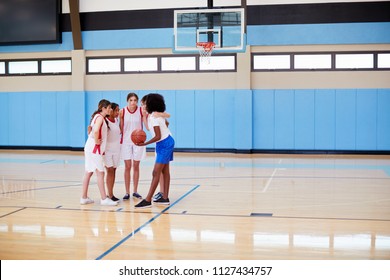 Female High School Basketball Players In Huddle Having Team Talk With Coach