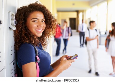 Female High School Student By Lockers Using Mobile Phone