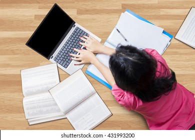 Female High School Student Lying Down On The Floor While Studying With Laptop And Books